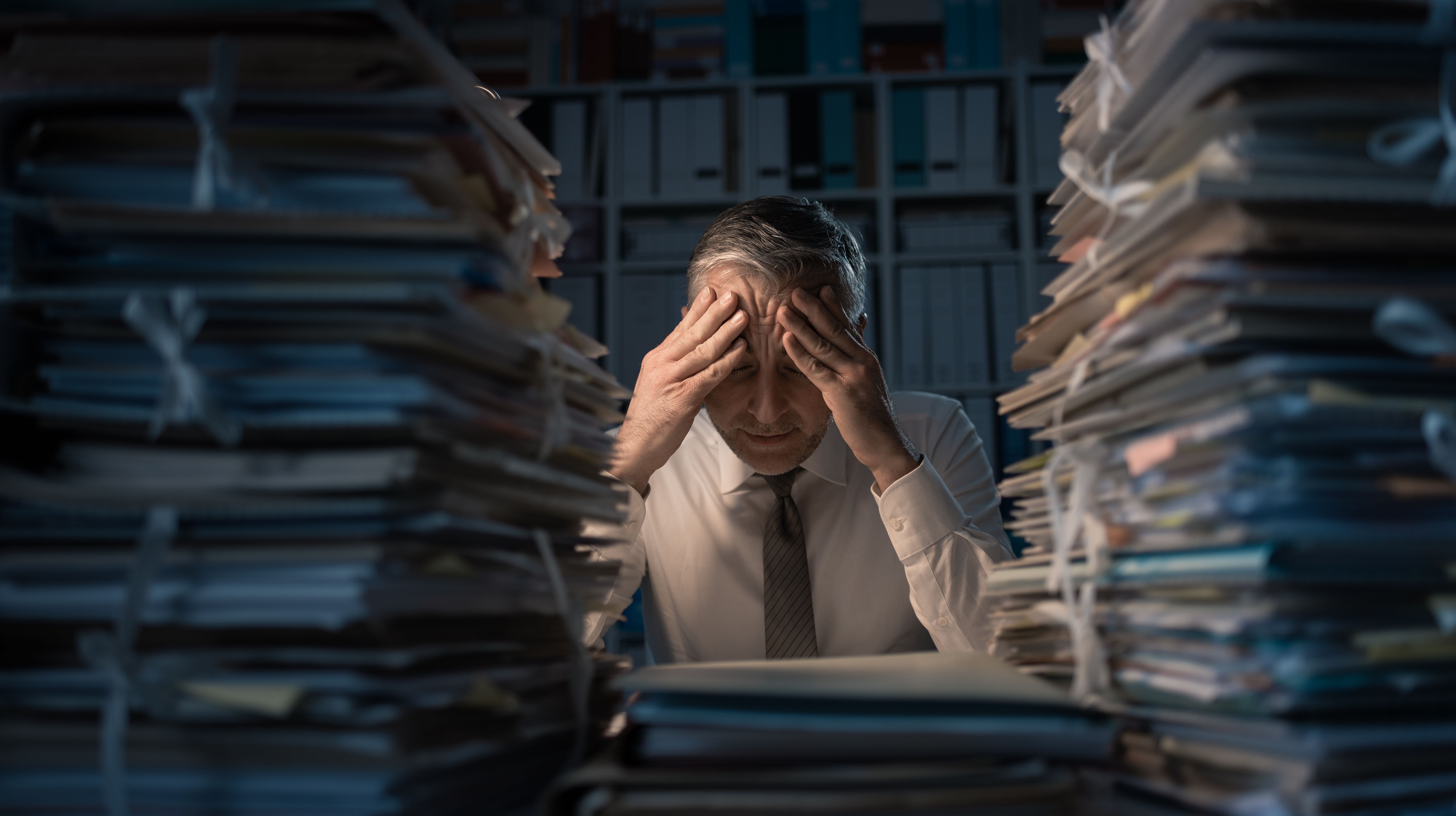 Man stressed out by mountains of work